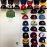 A wall of hanging hats, most of which are Minor League baseball hats. They're arranged in columns and rows around a closet door.
